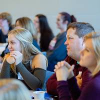 Alumni listening at a table to the speaker